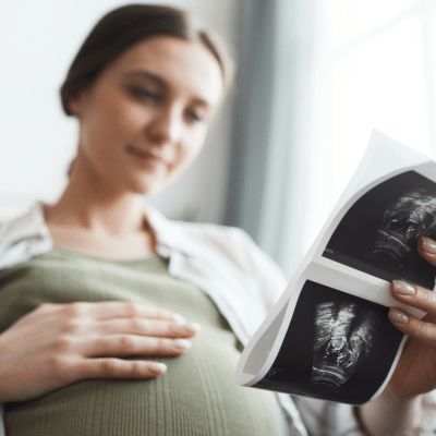 Woman holding belly looking at ultrasound photos during pregnancy