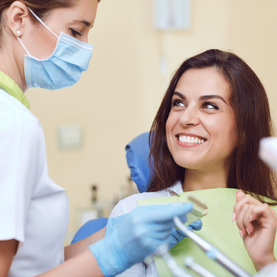 Woman smiling at the dentist office, representing dental implants vs bridges