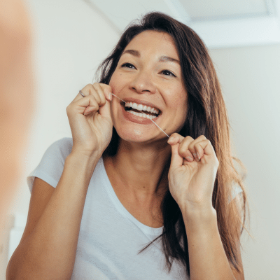 A woman flossing her teeth, representing brushing and flossing guide