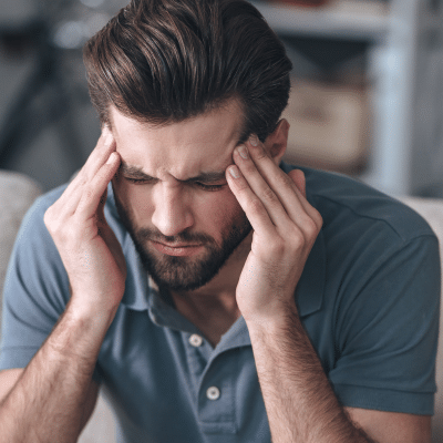 Man rubbing temples, showing signs of stress, representing how stress affects teeth and gums